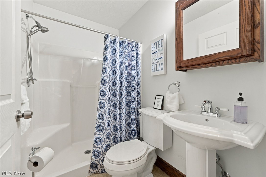 42764 Russia Road Elyria, OH 44035 - Photo 23 of 50 Pedestal sink with chrome fixtures, built-in shower with a bench, and a wood-framed medicine cabinet