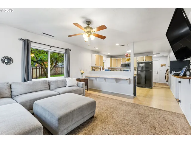a living room with furniture a large window with kitchen view