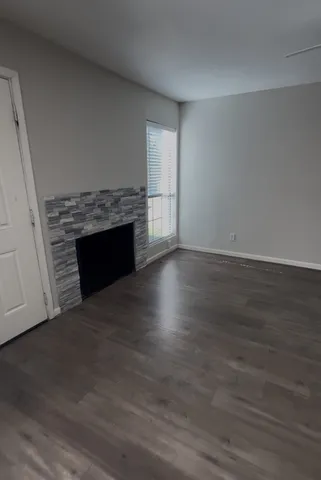 an empty room with wooden floor fireplace and windows