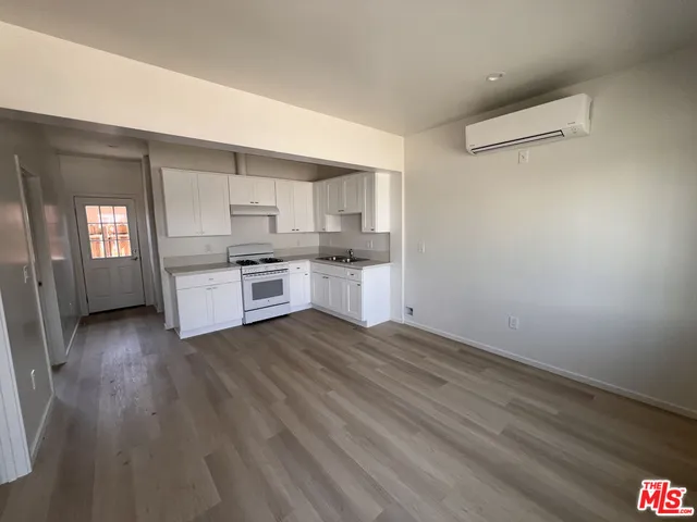 an empty room with wooden floor cabinet and windows