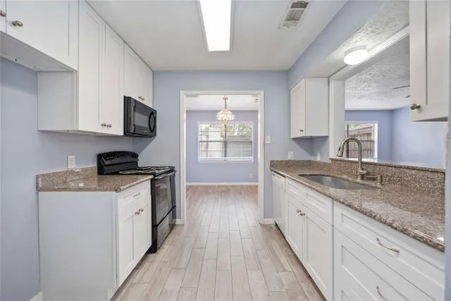 a kitchen with granite countertop wooden cabinets a sink and a stove