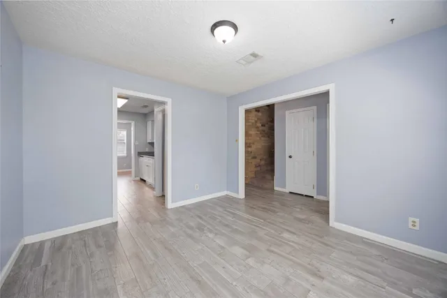 a view of an empty room with wooden floor and closet
