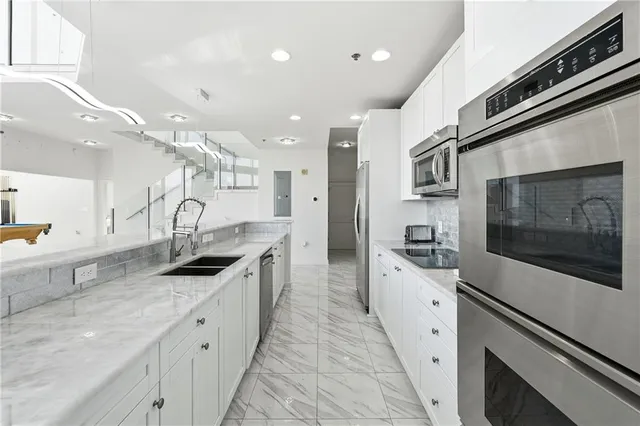 a large kitchen with stainless steel appliances a stove a sink and a refrigerator