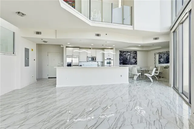 a living room with stainless steel appliances kitchen island granite countertop a sink and cabinets