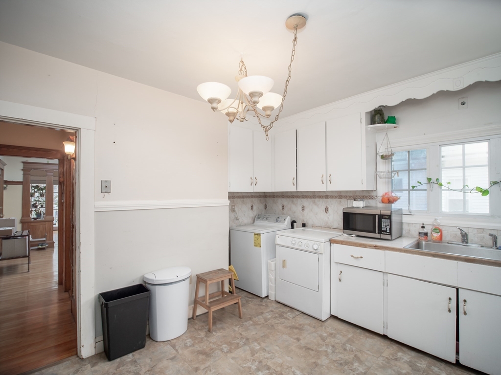 60 Powder House Boulevard, Unit 2 Somerville, MA 02144 - Photo 11 of 42 a kitchen with a sink dishwasher and white cabinets with wooden floor