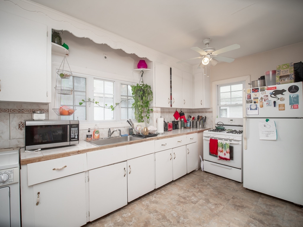 60 Powder House Boulevard, Unit 2 Somerville, MA 02144 - Photo 15 of 42 a kitchen with white cabinets and white appliances