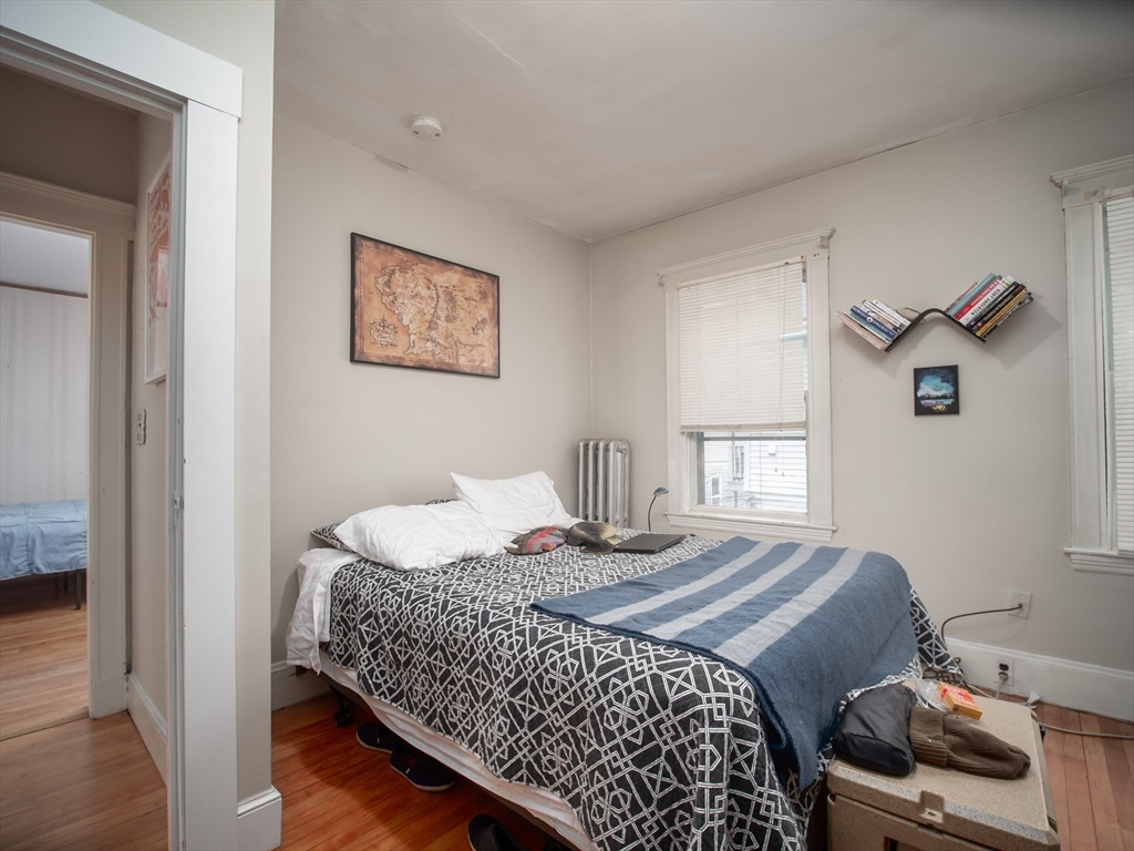 60 Powder House Boulevard, Unit 2 Somerville, MA 02144 - Photo 18 of 42 a bedroom with a bed and wooden floor
