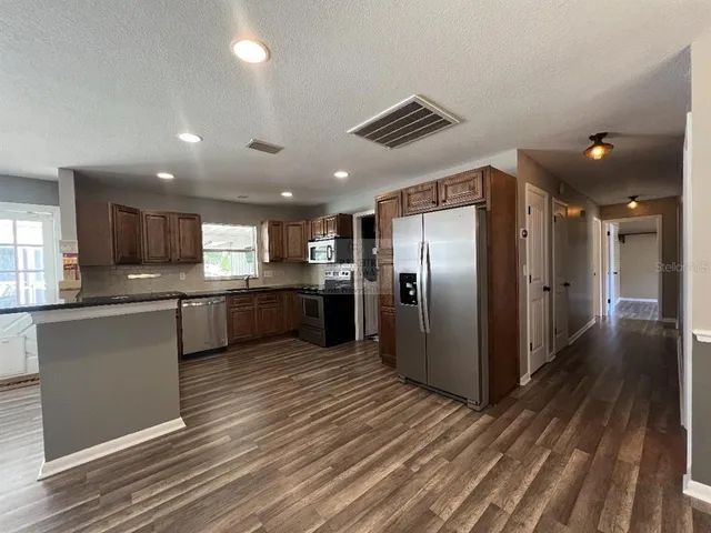 a view of an empty room with wooden floor and a ceiling fan
