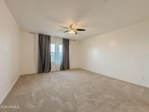 a view of an empty room with chandelier fan
