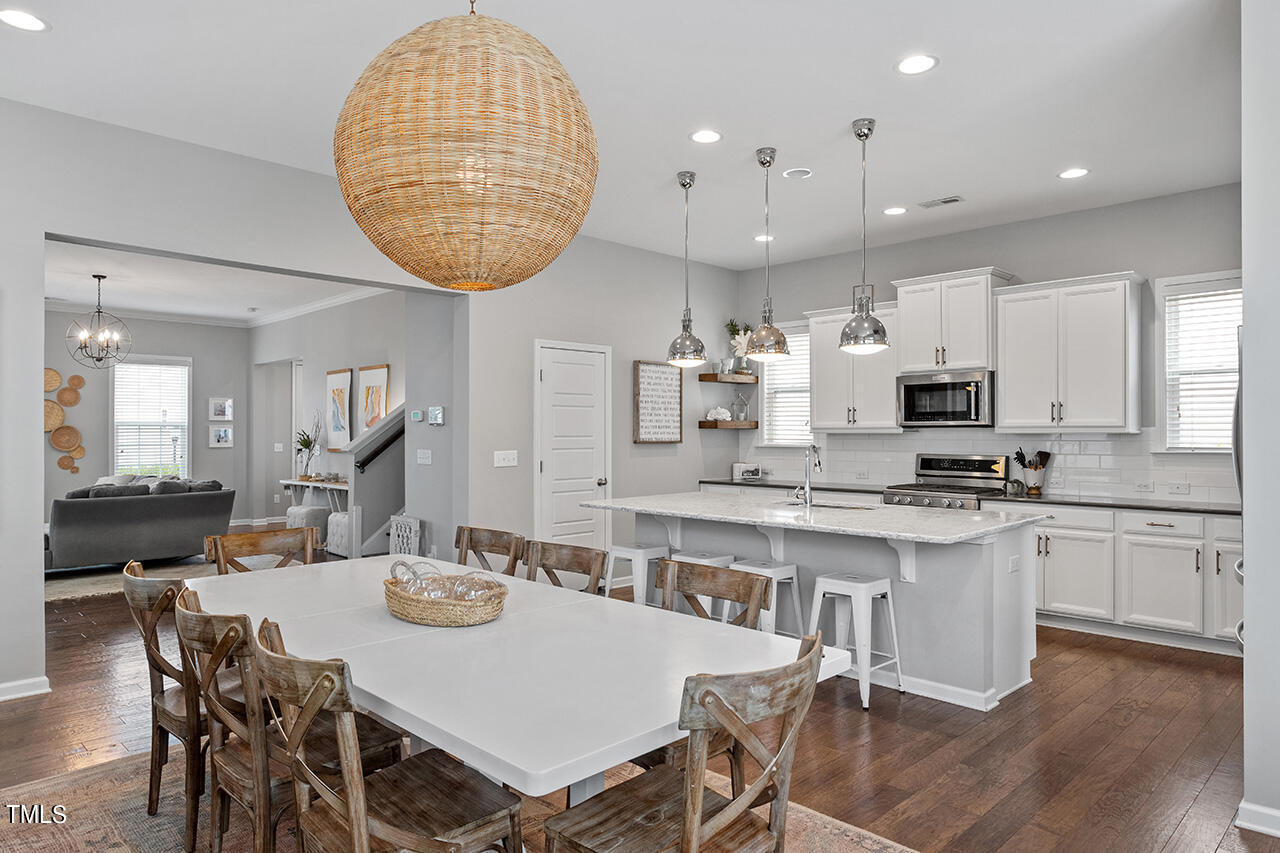 1616 Upper Park Road Wake Forest, NC 27587 - Photo 9 of 20 a kitchen with stainless steel appliances kitchen island granite countertop a dining table chairs and white cabinets