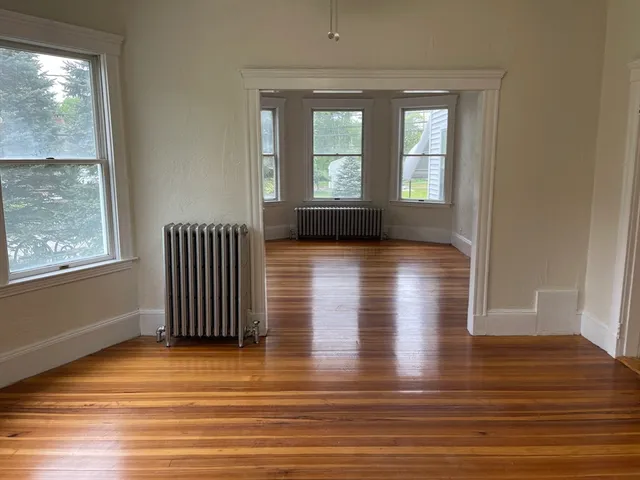 an empty room with wooden floor and windows