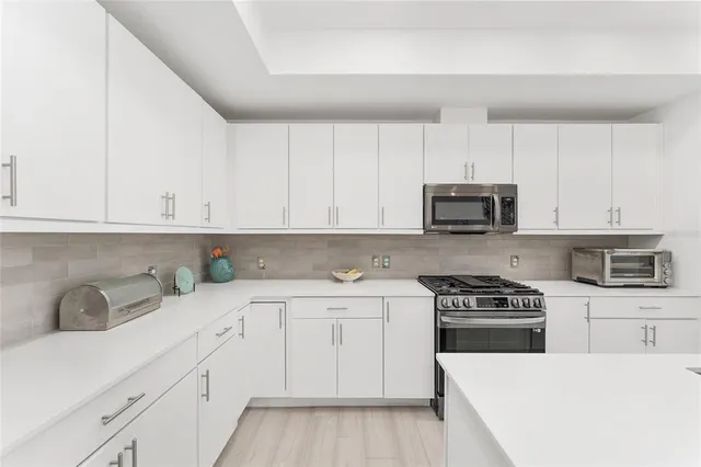 a kitchen with granite countertop white cabinets and stainless steel appliances