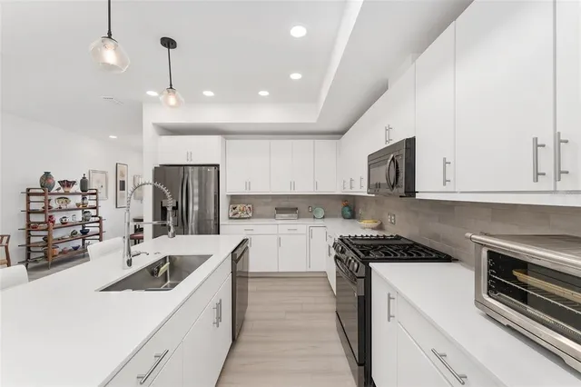 a kitchen with a sink stainless steel appliances and white cabinets
