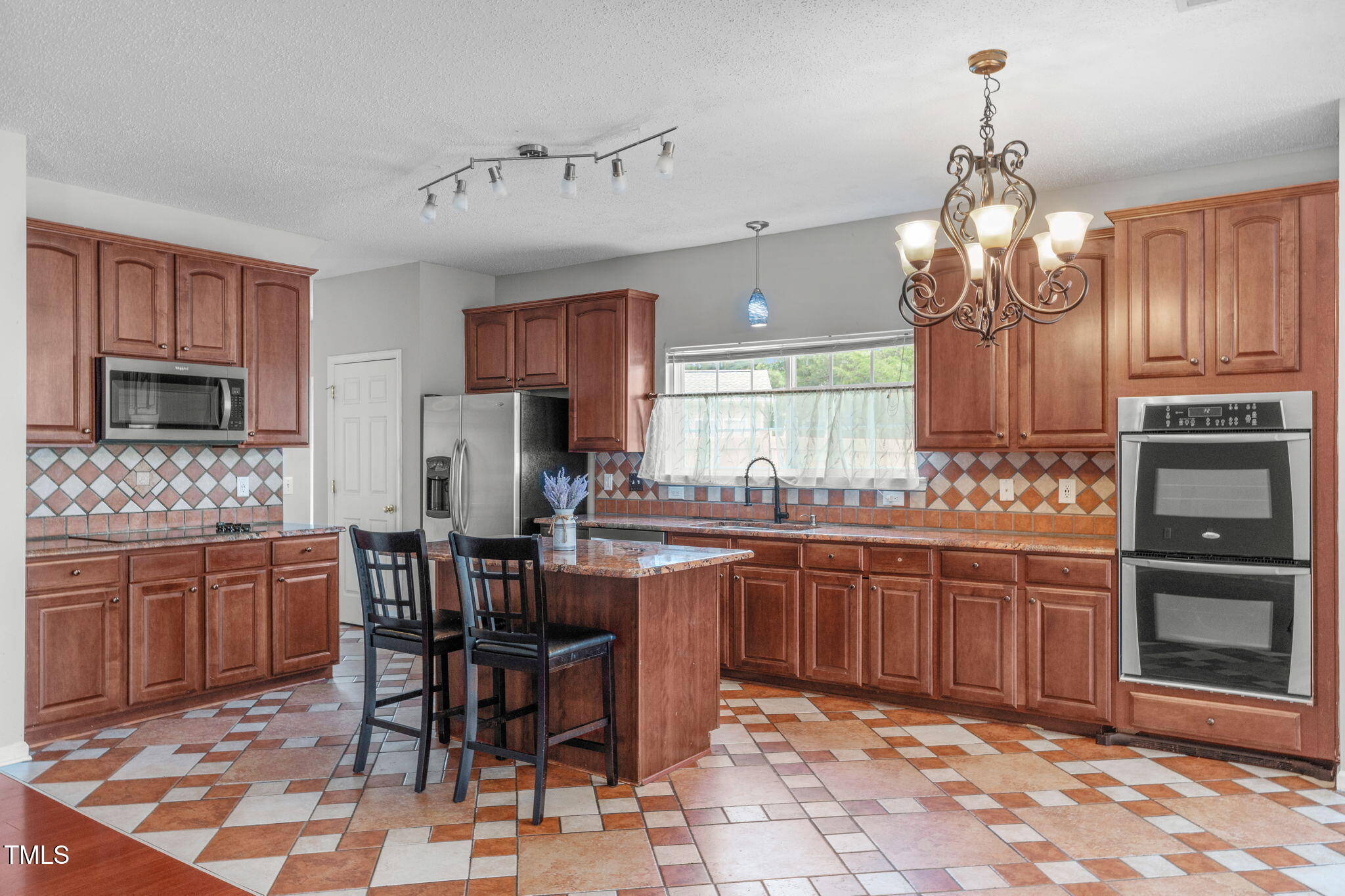 760 Stackhurst Way Wake Forest, NC 27587 - Photo 3 of 37 a kitchen with stainless steel appliances granite countertop wooden cabinets a dining table and chairs