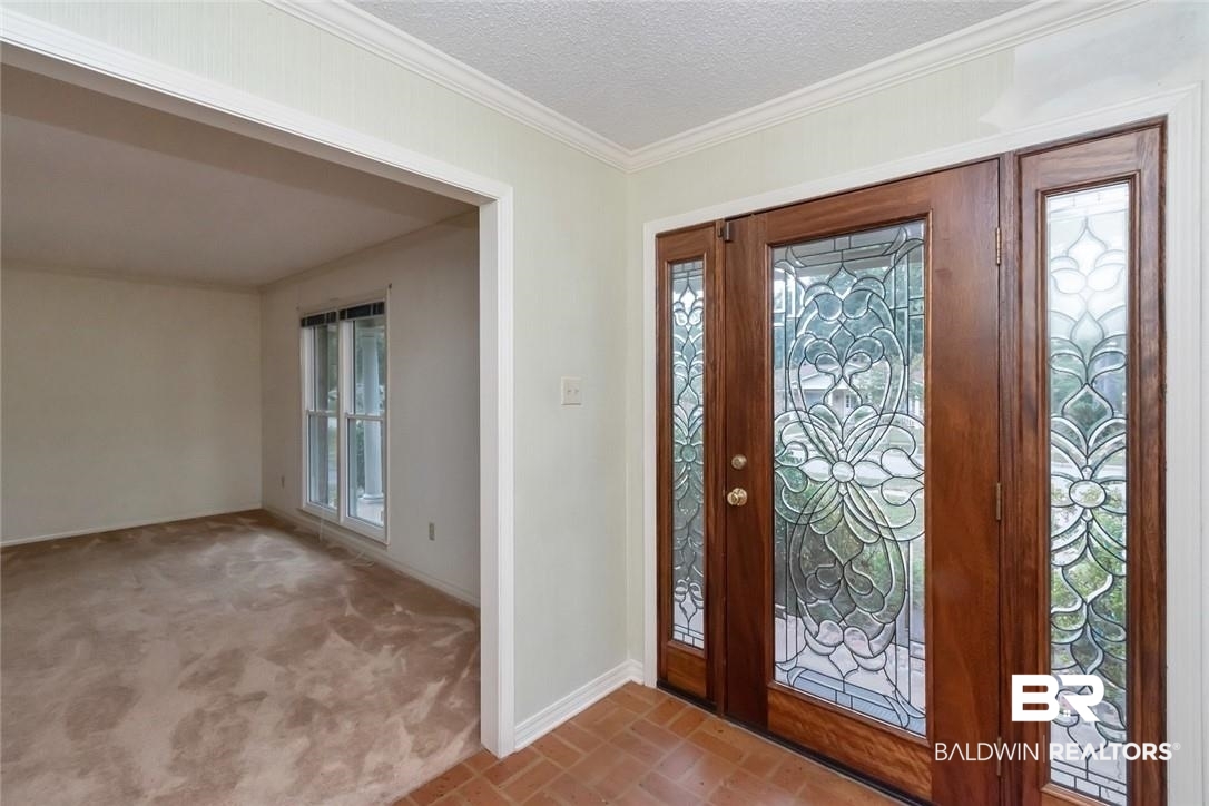 6109 Timberly Road North Mobile, AL 36609 - Photo 11 of 26 Foyer entrance featuring light carpet, a textured ceiling, and crown molding
