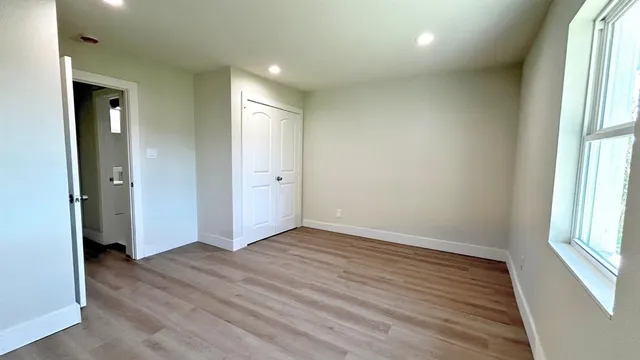 an empty room with wooden floor and windows