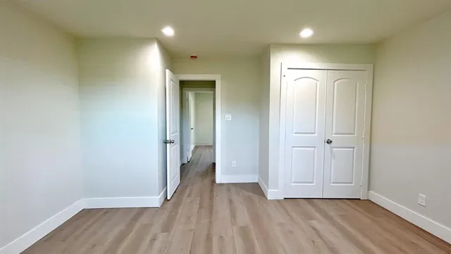 a view of a hallway with wooden floor and closet area