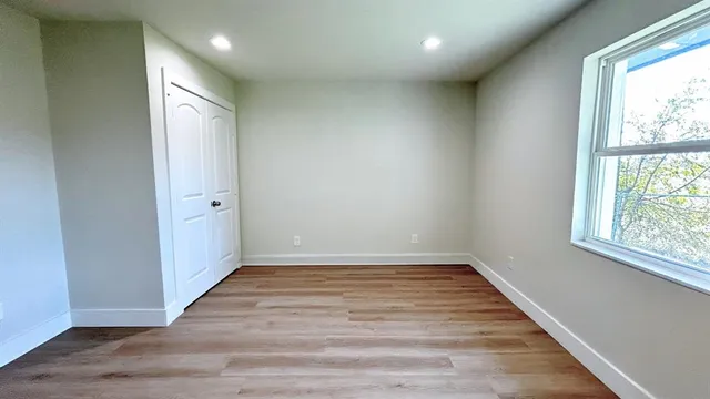 an empty room with wooden floor and windows