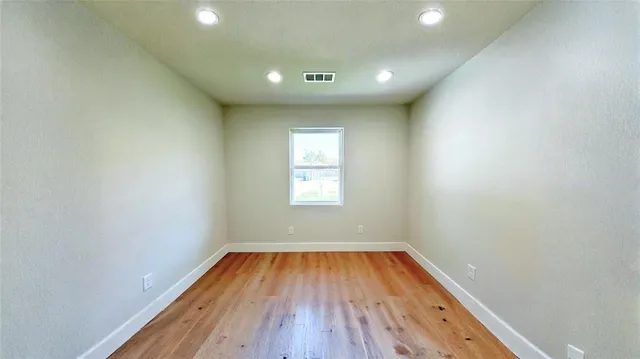 a view of empty room with wooden floor