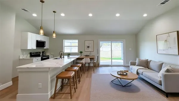 a living room with furniture kitchen view and a wooden floor