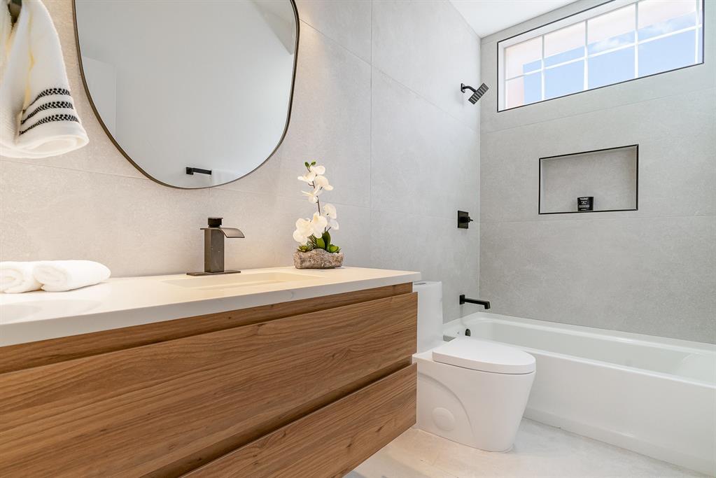 7524 Aberdon Road Dallas, TX 75252 - Photo 19 of 39 Bathroom featuring shower / washtub combination, vanity, toilet, and tile walls