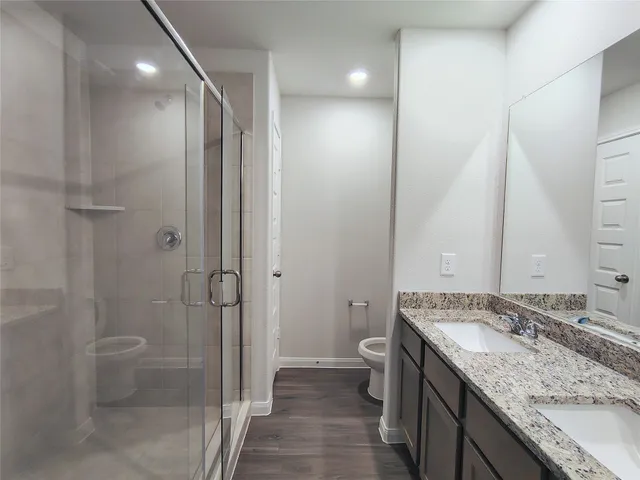a bathroom with a granite countertop sink a toilet and shower