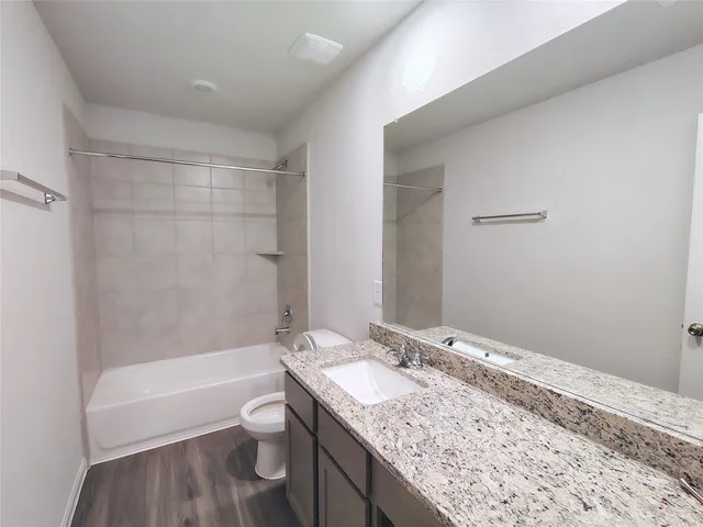 a bathroom with a granite countertop sink a toilet and bathtub