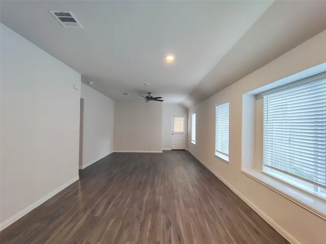 a view of empty room with wooden floor and fan