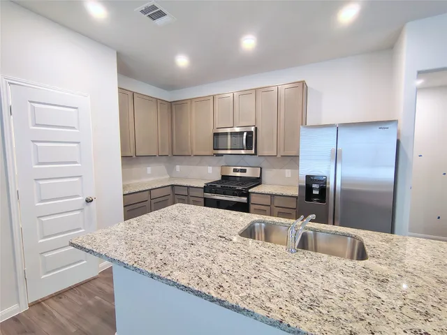 a kitchen with granite countertop a refrigerator and a sink