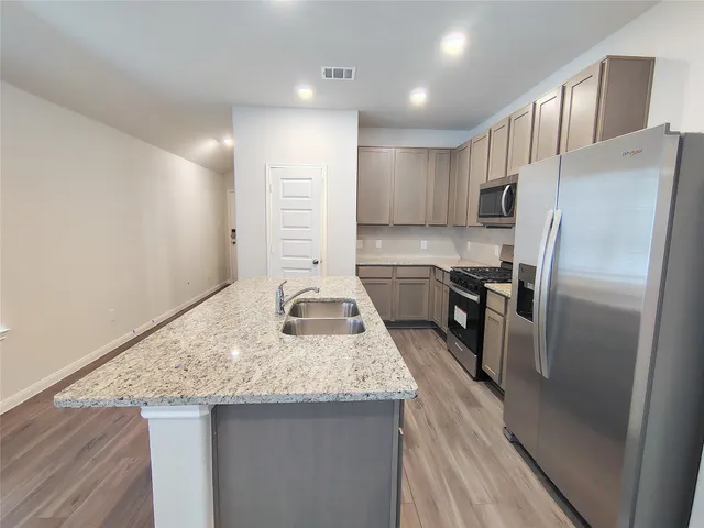 a kitchen with stainless steel appliances granite countertop a refrigerator a stove and a wooden floors