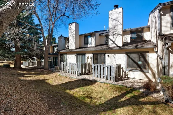 a view of a brick house with large trees and a small yard