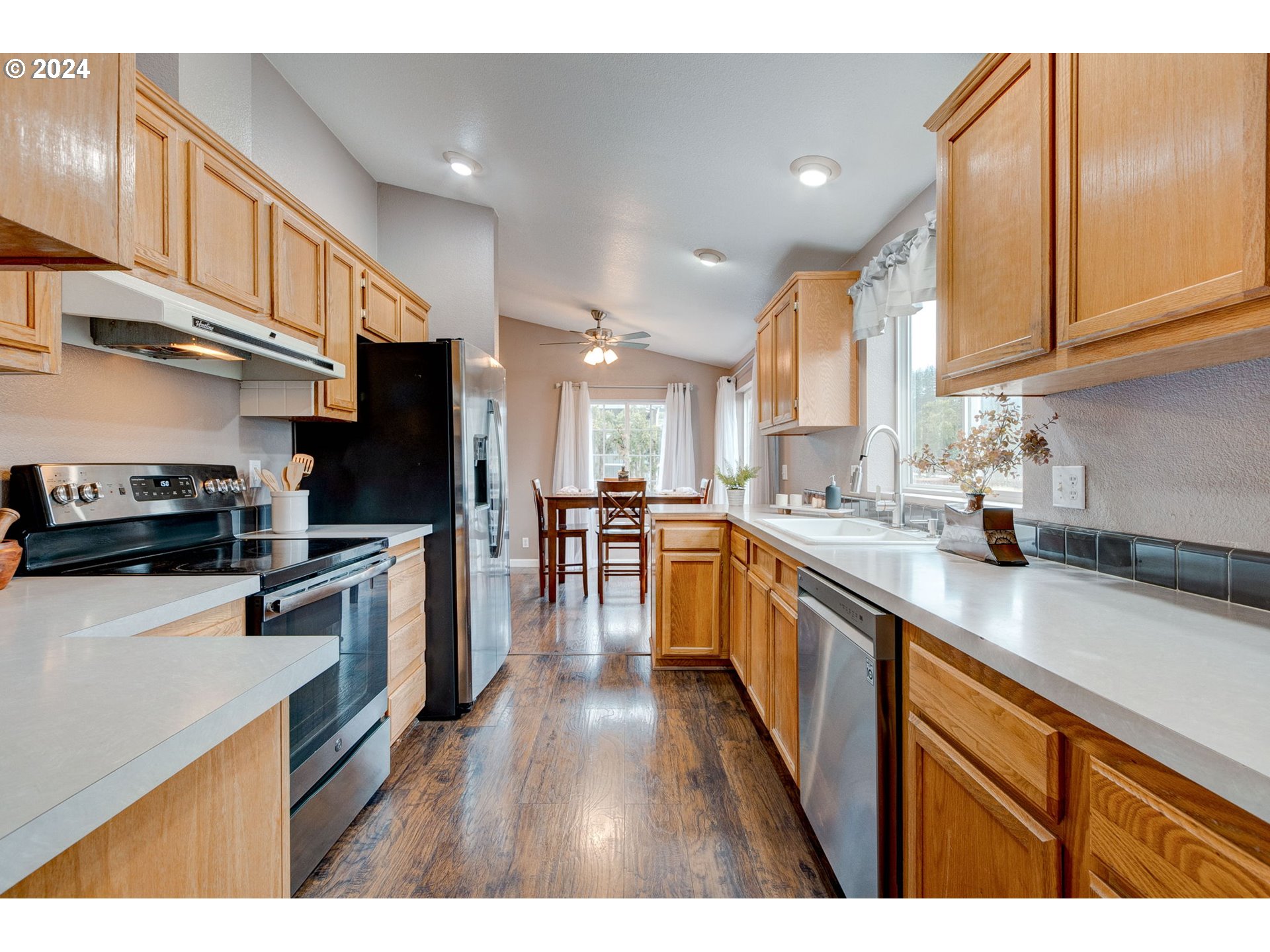 22120 Southwest Riggs Road Beaverton, OR 97078 - Photo 6 of 35 a kitchen with stainless steel appliances granite countertop a refrigerator a sink dishwasher a stove and white countertops with wooden floor
