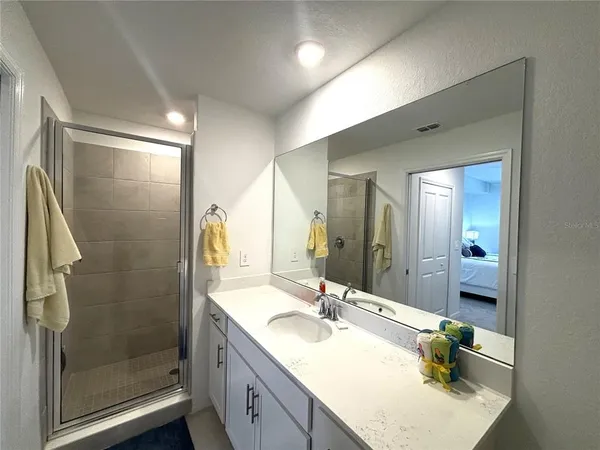 a bathroom with a granite countertop sink a mirror and shower