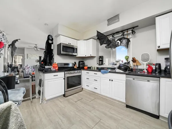a kitchen with stainless steel appliances a stove a sink cabinets and a living room view