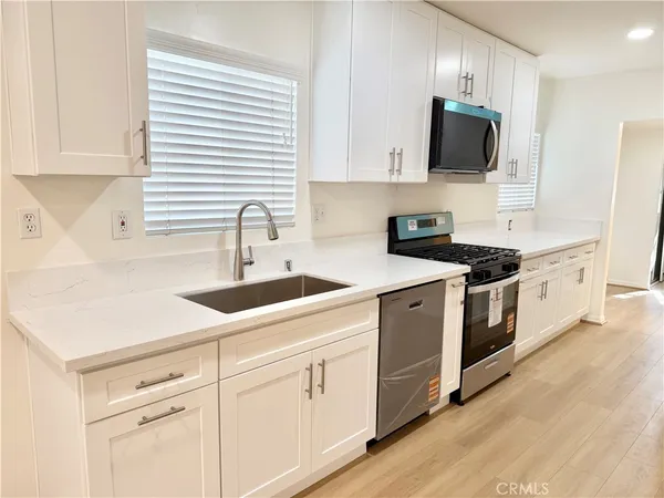 a large kitchen with a sink and dishwasher a stove top oven