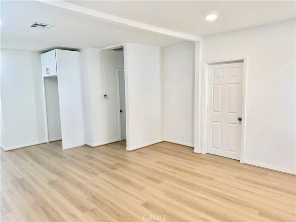 an empty room with wooden floor and mirror