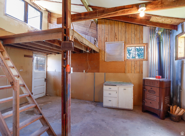155 West Center Street Fillmore, UT 84631 - Photo 83 of 86 Interior space featuring exposed wood beams, a loft area with wood stairs, a built-in wood-burning stove with a metal flue, wood paneling, and multiple windows