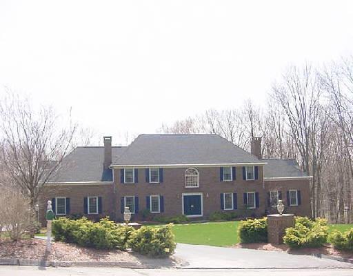 a view of a brick house next to a yard with large trees