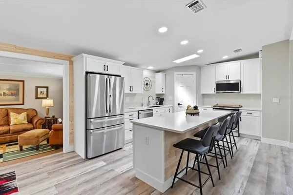 a kitchen with a refrigerator a stove a sink and a dining table with wooden floor