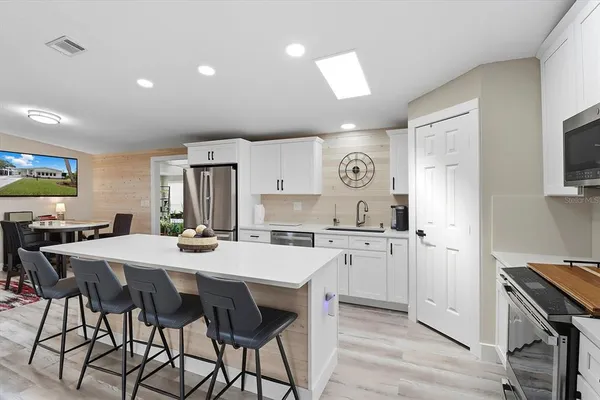 a open kitchen with stainless steel appliances granite countertop a stove a refrigerator a kitchen island a table and chairs