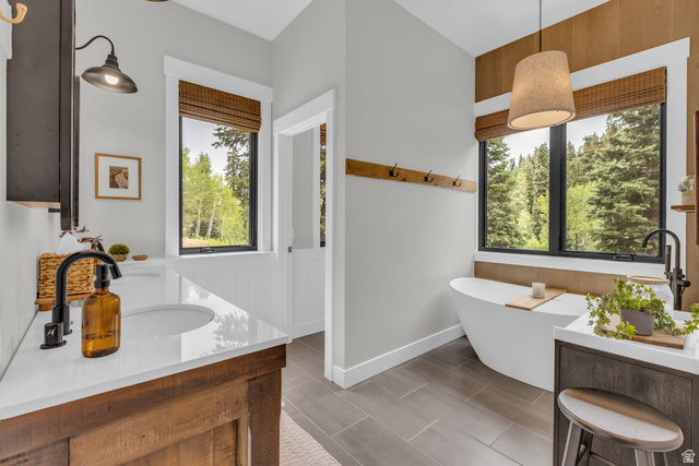 1766 West Tollgate Cyn Road Coalville, UT 84017 - Photo 18 of 59 Bathroom featuring a freestanding soaking tub, wood-finish flooring, two large windows with woven blinds, and a double vanity with stone countertops