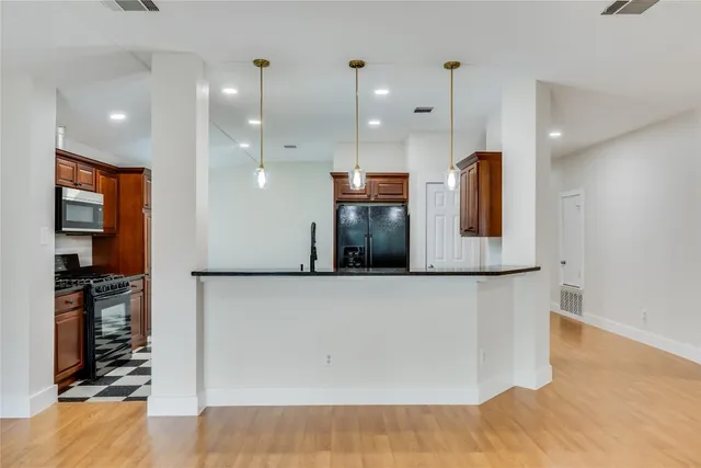 a kitchen with stainless steel appliances granite countertop a refrigerator a stove and a sink with wooden floor