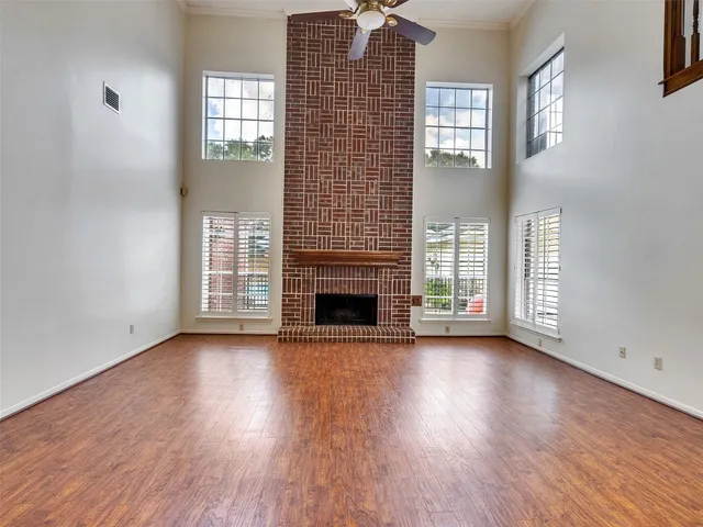 an empty room with wooden floor fireplace and windows
