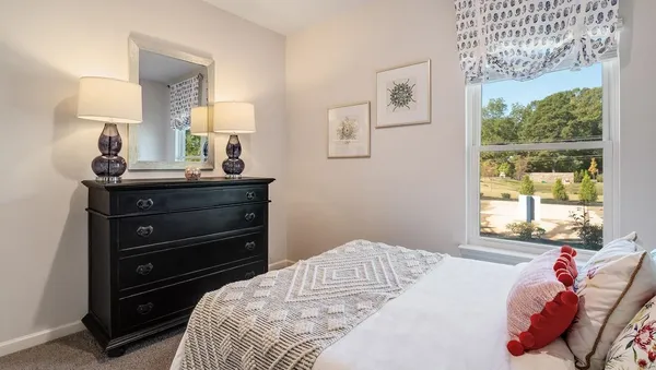 a bedroom with a bed and a dresser next to a window