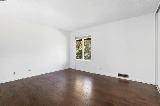 an empty room with wooden floor and window
