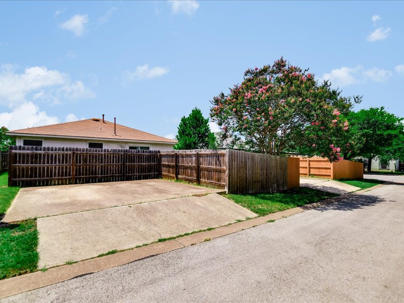 13827 Spring Heath Road Pflugerville, TX 78660 - Photo 20 of 20 A well-maintained wooden fence encloses a private yard with a blooming Crepe Myrtle, complementing the home's exterior.