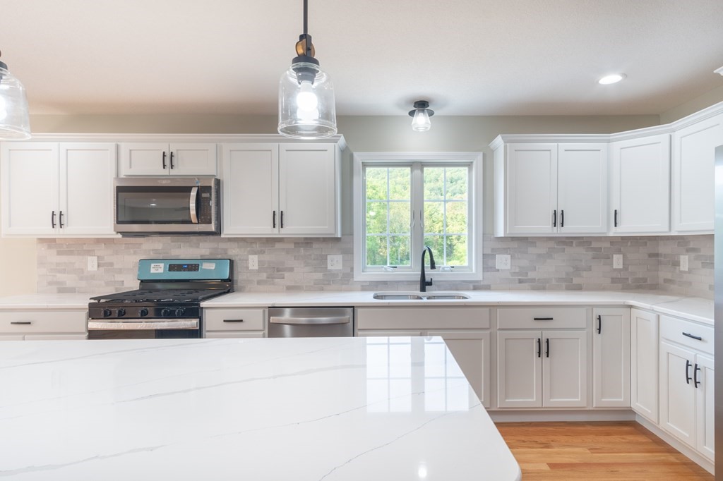 2 Upper Palmer Road Monson, MA 01057 - Photo 5 of 41 a kitchen with granite countertop white cabinets a sink and a oven with wooden floor