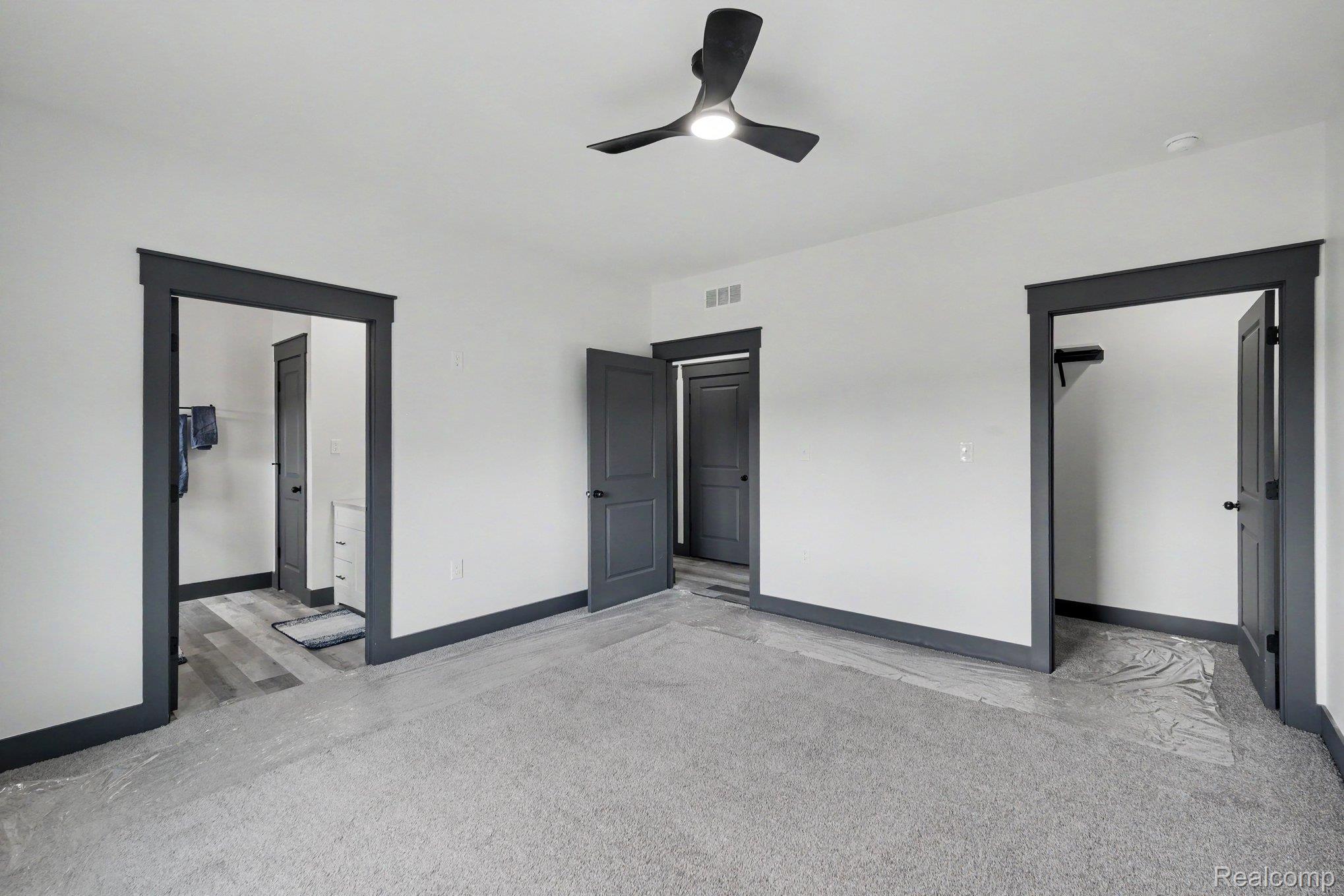 12425 Miller Road Lennon, MI 48449 - Photo 19 of 26 Bright interior space featuring a ceiling fan with integrated lighting, grey carpeting, and dark trim