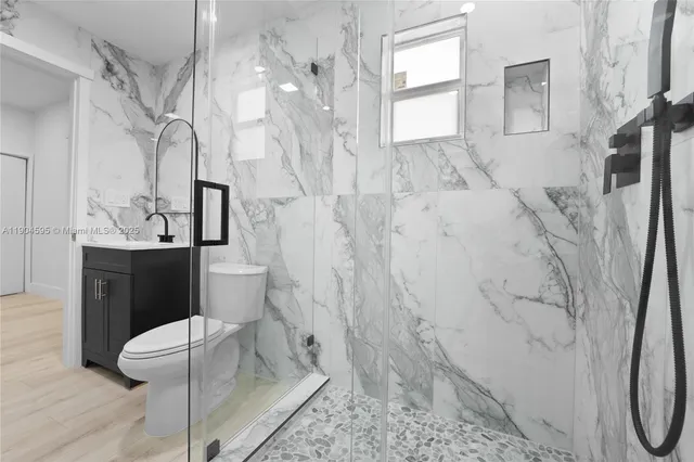 a bathroom with a granite countertop sink a toilet and a shower