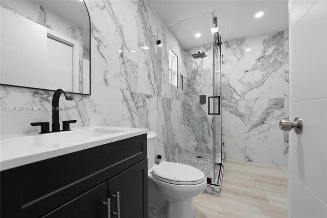 a bathroom with a sink a toilet a mirror and shower